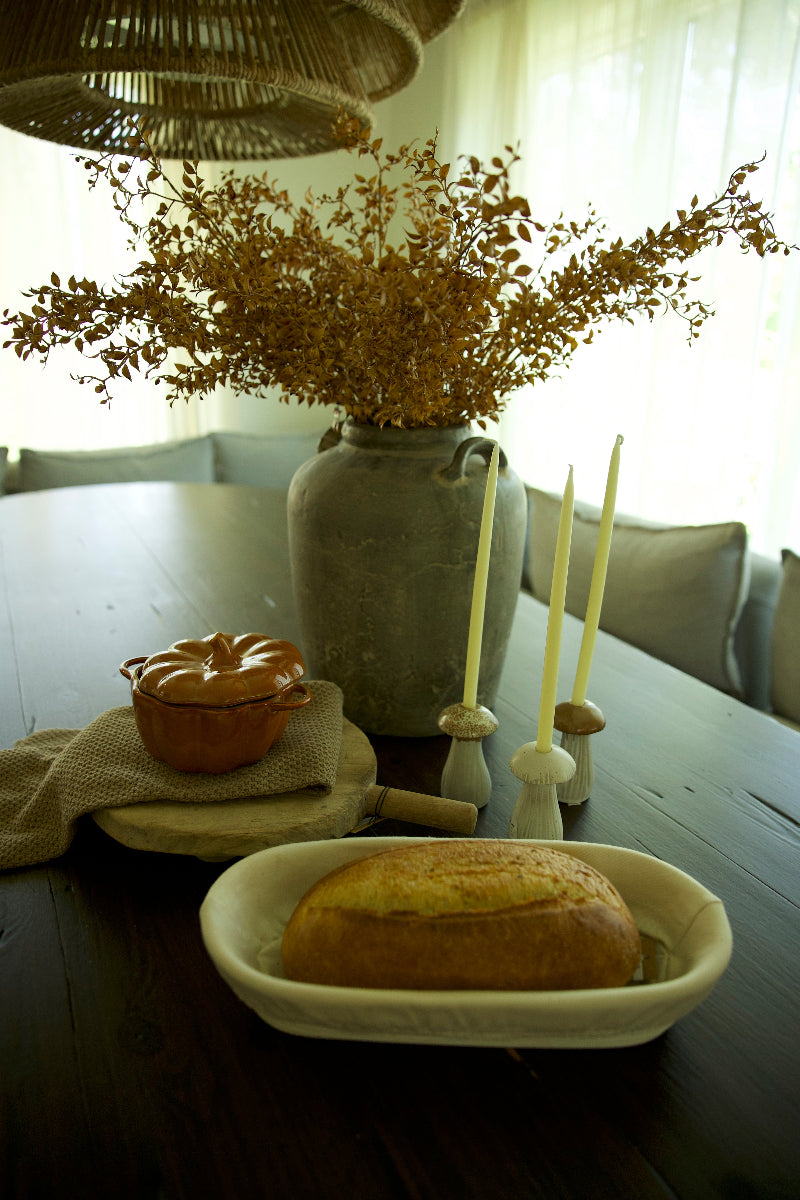 Table setting with bread, vase of flowers, and candles in a homey kitchen.