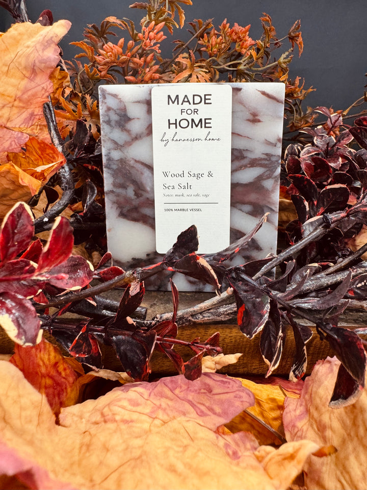 Candle surrounded by dried leaves and plants